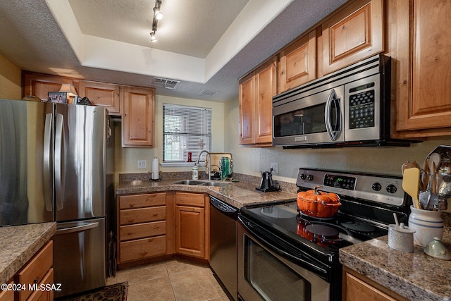 kitchen with sink, stainless steel appliances, a textured ceiling, track lighting, and light tile patterned flooring