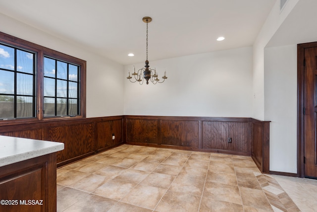 unfurnished dining area with a chandelier and wooden walls