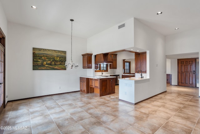 kitchen with sink, premium range hood, kitchen peninsula, a towering ceiling, and pendant lighting