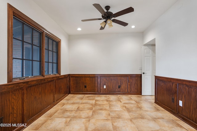 unfurnished room featuring wooden walls and ceiling fan