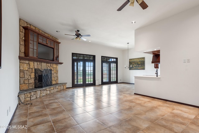 unfurnished living room featuring a fireplace, ceiling fan, and french doors