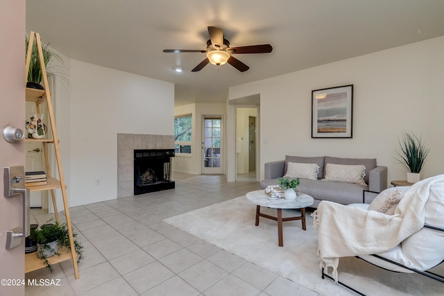 living room featuring a fireplace, ceiling fan, and light tile patterned flooring