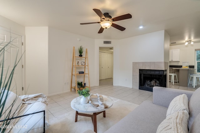 living room featuring ceiling fan, light tile patterned floors, and a tiled fireplace