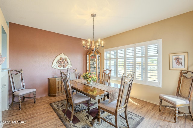 dining area featuring light wood-type flooring and an inviting chandelier