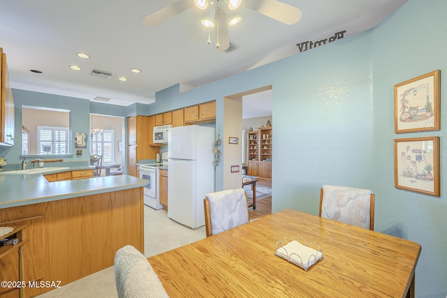 kitchen with white appliances, sink, ceiling fan, light tile patterned flooring, and kitchen peninsula