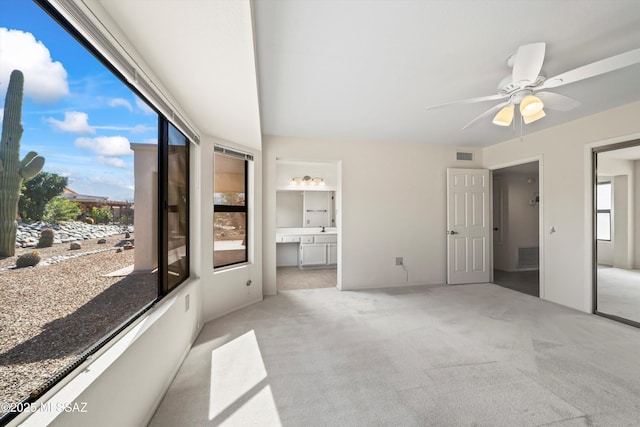 unfurnished bedroom featuring visible vents, ensuite bathroom, a ceiling fan, and light colored carpet