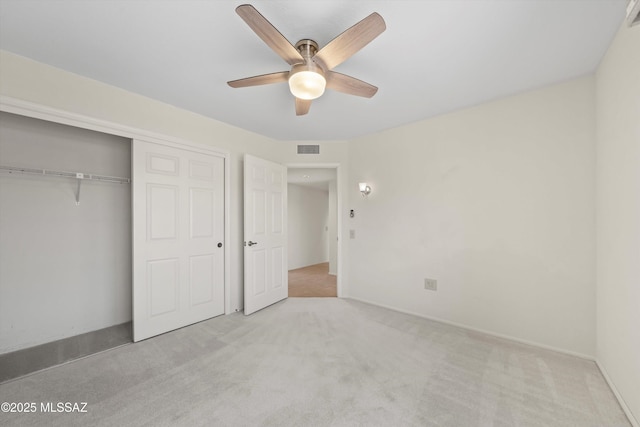 unfurnished bedroom featuring a closet, carpet, visible vents, and a ceiling fan