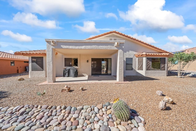 rear view of house featuring a patio, a tiled roof, and stucco siding