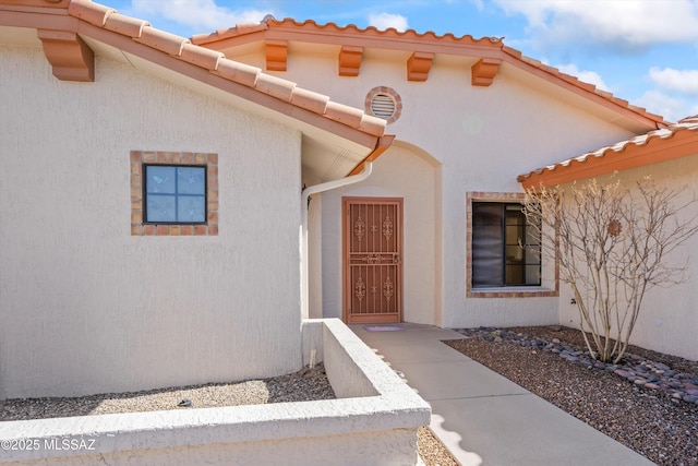 view of exterior entry featuring a tile roof and stucco siding