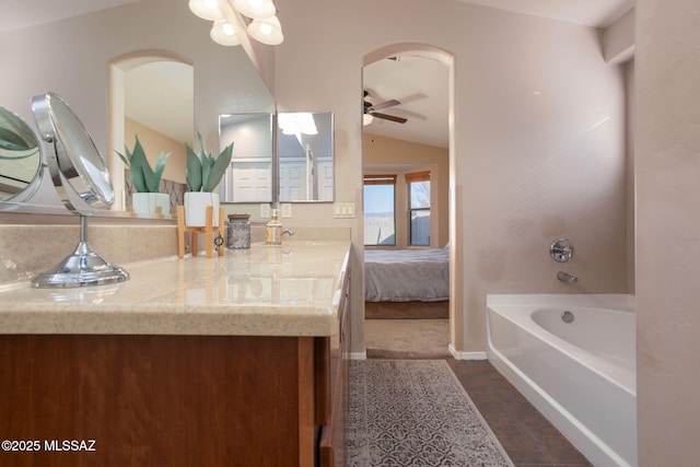 bathroom with a tub to relax in, ceiling fan, vanity, and lofted ceiling