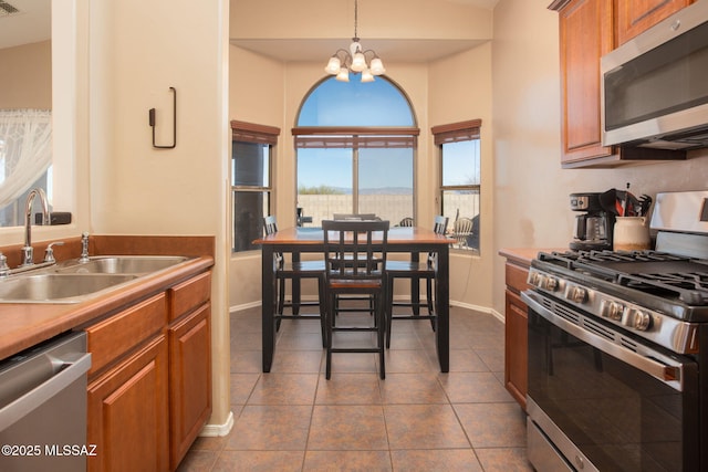 kitchen featuring appliances with stainless steel finishes, dark tile patterned floors, sink, a chandelier, and hanging light fixtures