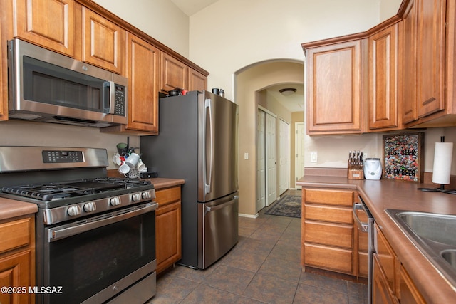 kitchen with dark tile patterned flooring, sink, and appliances with stainless steel finishes