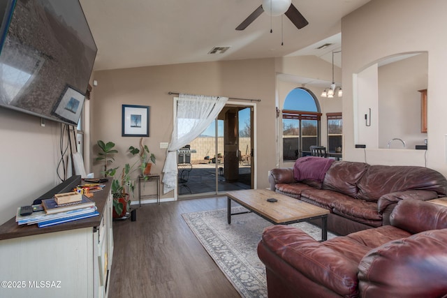 living room with ceiling fan with notable chandelier, dark hardwood / wood-style flooring, and lofted ceiling