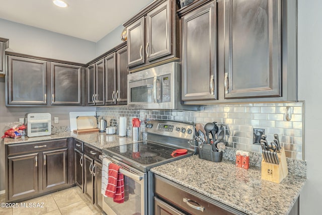 kitchen with decorative backsplash, light tile patterned floors, light stone counters, dark brown cabinetry, and stainless steel appliances