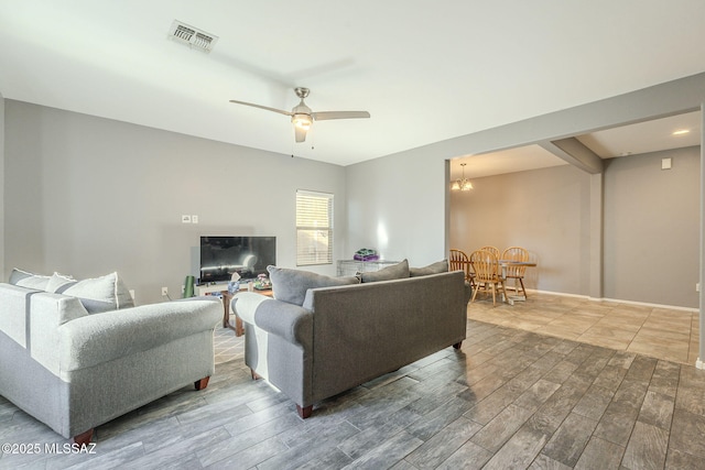 living room with ceiling fan with notable chandelier
