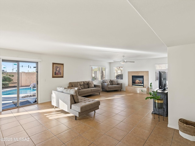 tiled living room with ceiling fan and a tile fireplace