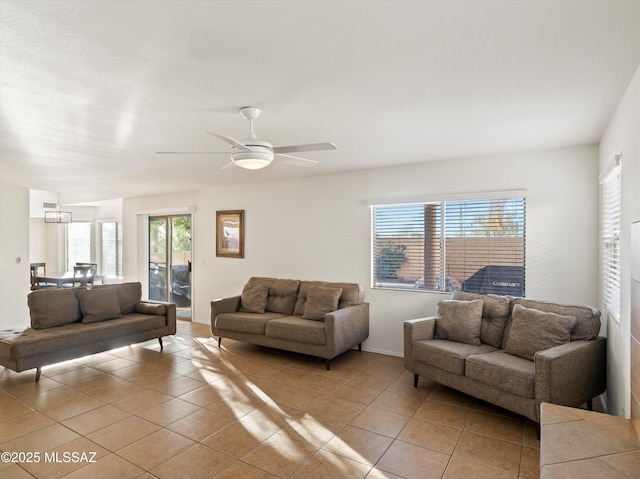 tiled living room with ceiling fan with notable chandelier