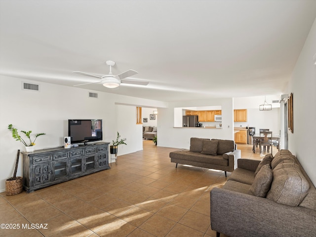 living room with ceiling fan with notable chandelier and tile patterned floors