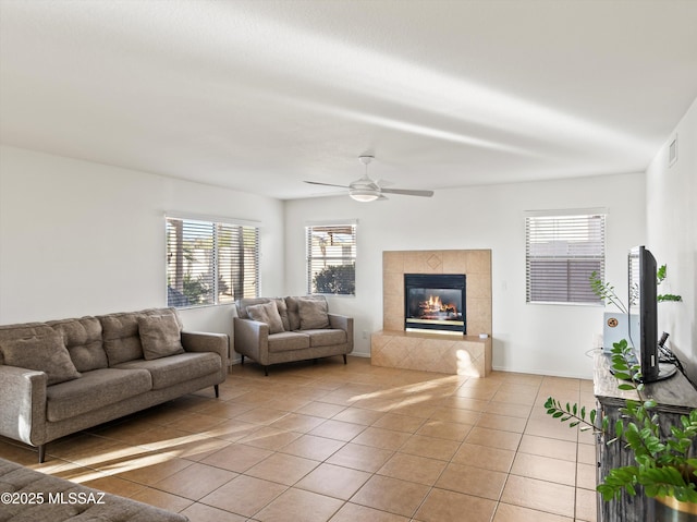 living room with ceiling fan, tile patterned floors, and a tile fireplace