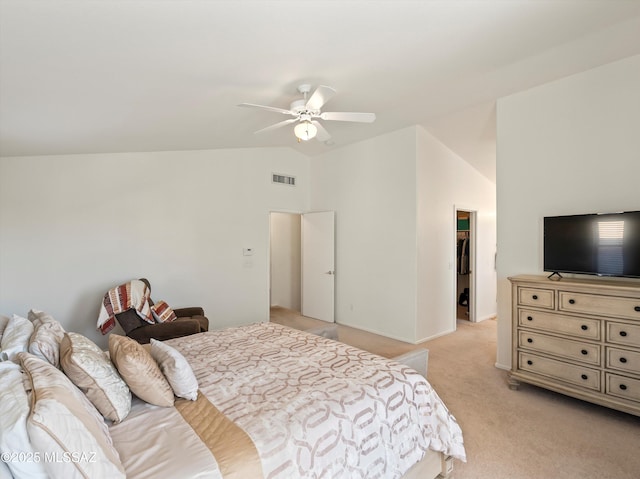 carpeted bedroom with ceiling fan, a closet, a walk in closet, and vaulted ceiling