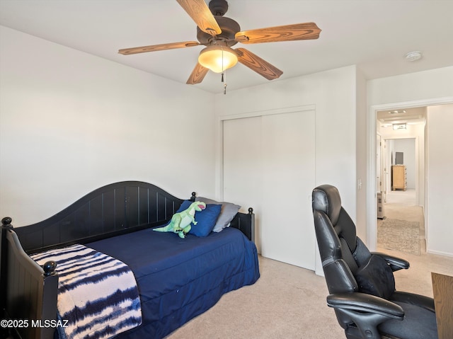 carpeted bedroom featuring ceiling fan and a closet