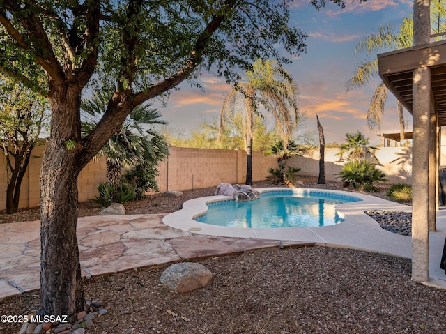 pool at dusk with a patio area