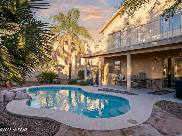 pool at dusk with a patio area