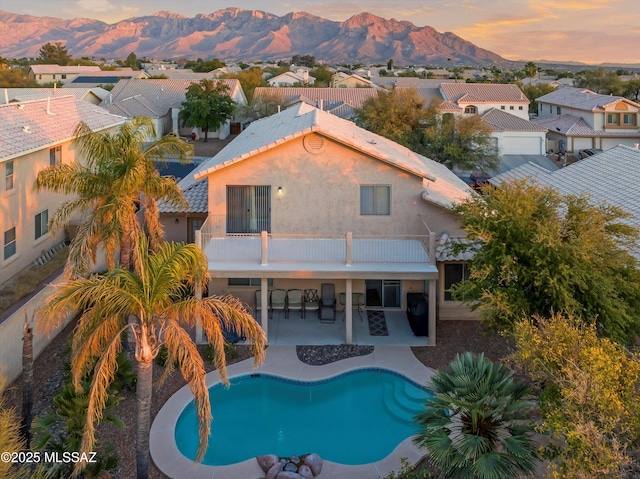 pool at dusk featuring a patio area and a mountain view