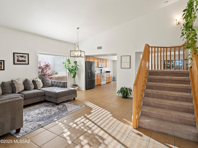 living room featuring light tile patterned floors, lofted ceiling, and a notable chandelier