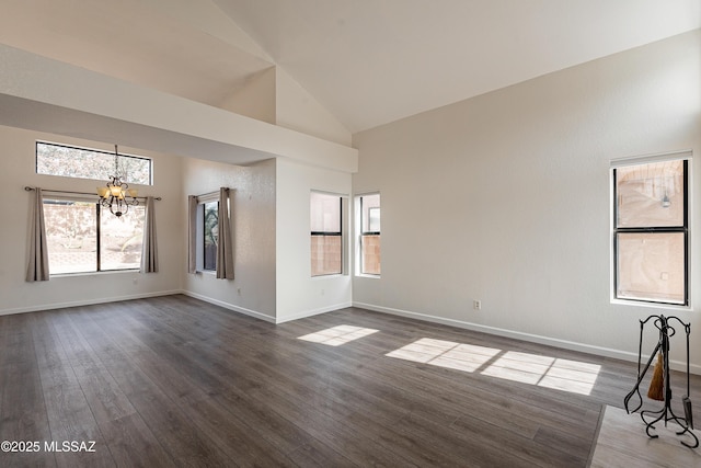 spare room featuring baseboards, dark wood finished floors, a wealth of natural light, and a notable chandelier