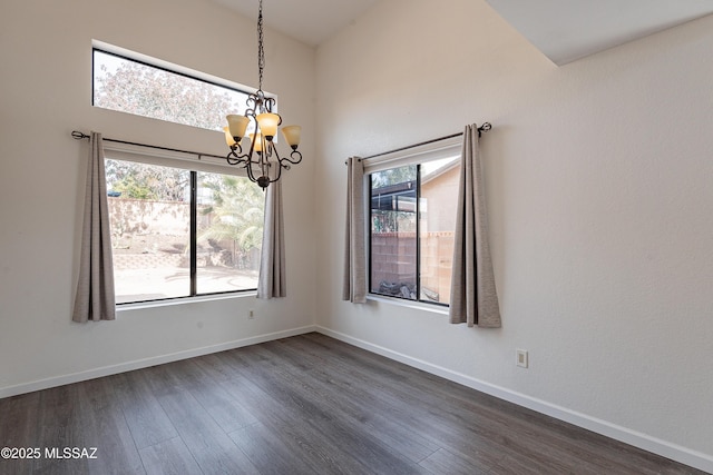 spare room featuring dark hardwood / wood-style flooring and a notable chandelier