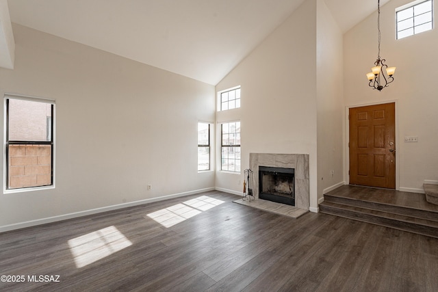 unfurnished living room featuring high vaulted ceiling, a chandelier, a fireplace, and dark hardwood / wood-style flooring