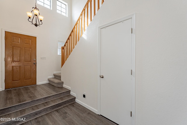 foyer featuring dark hardwood / wood-style floors, a notable chandelier, and a towering ceiling