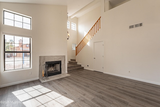 unfurnished living room featuring hardwood / wood-style flooring, a high ceiling, a fireplace, and beamed ceiling