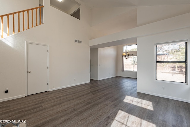 unfurnished living room featuring dark hardwood / wood-style flooring, a chandelier, and a high ceiling