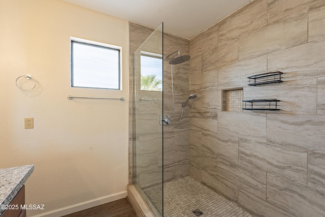 bathroom with a tile shower and vanity