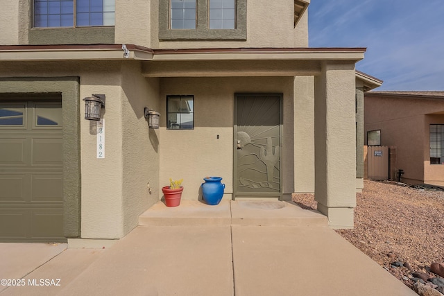 entrance to property featuring a garage and stucco siding