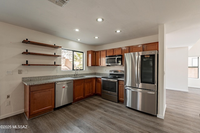 kitchen featuring stainless steel appliances, dark hardwood / wood-style floors, light stone countertops, and sink