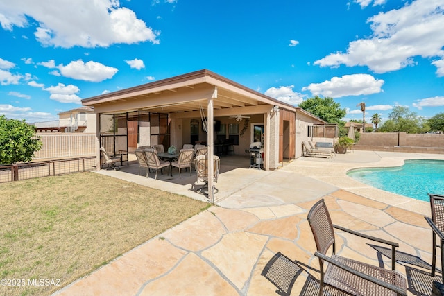 rear view of property featuring a fenced in pool, a yard, and a patio area