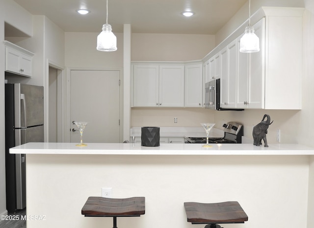 kitchen with kitchen peninsula, a breakfast bar, stainless steel appliances, decorative light fixtures, and white cabinetry