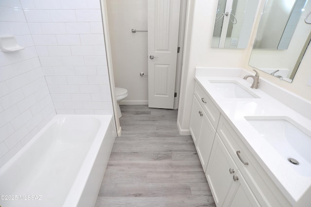 full bathroom with toilet, vanity, tiled shower / bath combo, and hardwood / wood-style flooring