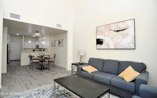 living room with light wood-type flooring and a towering ceiling