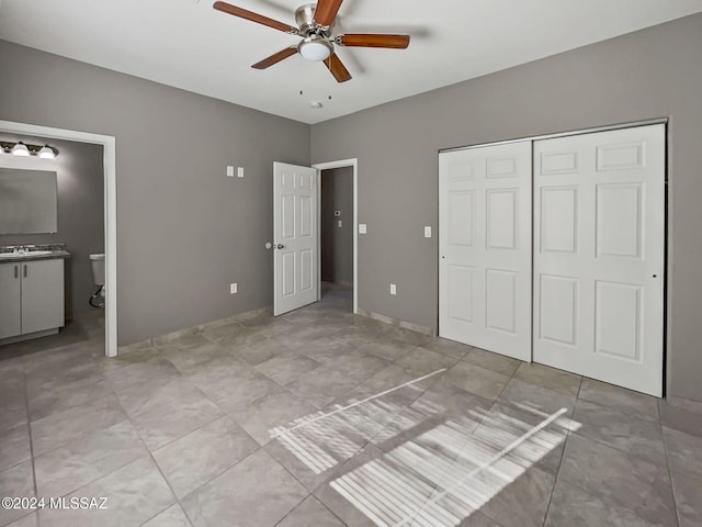 unfurnished bedroom featuring ensuite bath, ceiling fan, a closet, and light tile patterned flooring