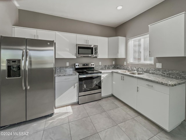 kitchen featuring sink, white cabinets, light tile patterned flooring, and appliances with stainless steel finishes