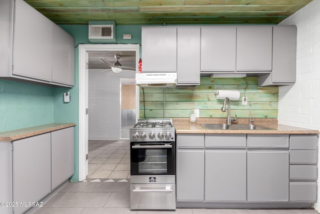 kitchen with wooden ceiling, light tile patterned floors, sink, and high end stainless steel range oven