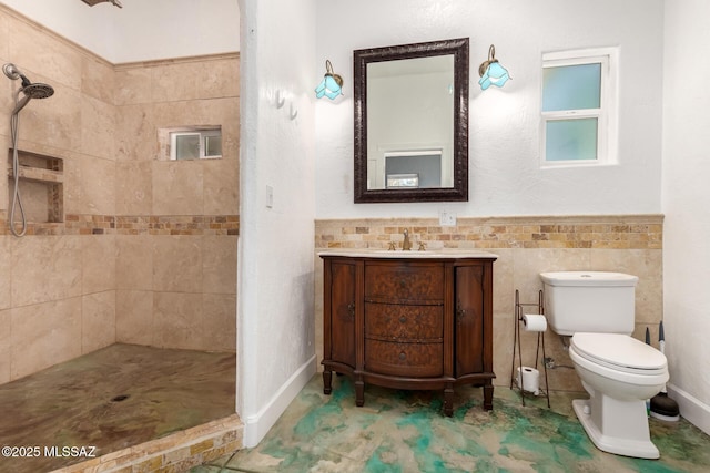 bathroom featuring toilet, a tile shower, tile walls, and vanity