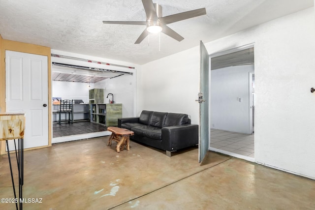 living room featuring a textured ceiling, ceiling fan, and concrete floors