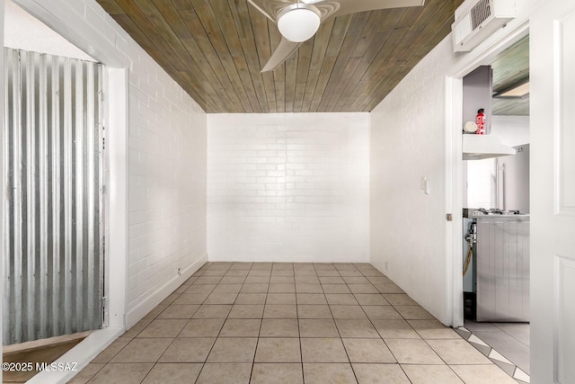 unfurnished room with light tile patterned floors, wood ceiling, and brick wall