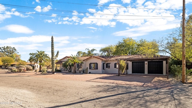 mediterranean / spanish-style house with a tiled roof, an attached garage, driveway, and stucco siding