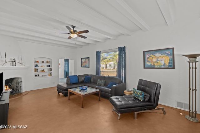 living room with built in features, a ceiling fan, arched walkways, a lit fireplace, and beamed ceiling